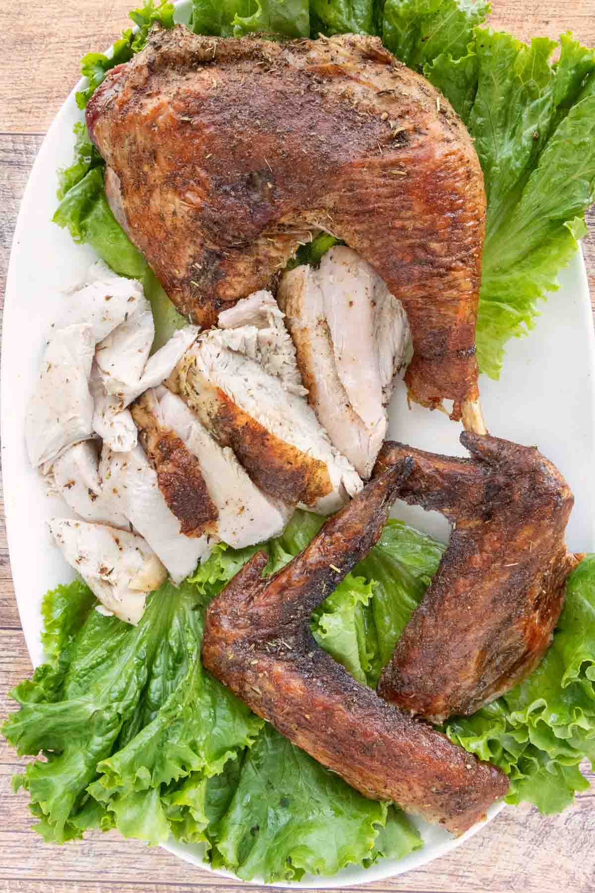 Cut up Spatchcock Turkey on a platter lined with romaine leaves.