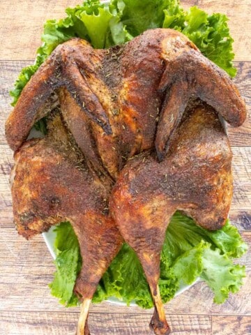 Roasted Spatchcock Turkey on a platter lined with romaine leaves.