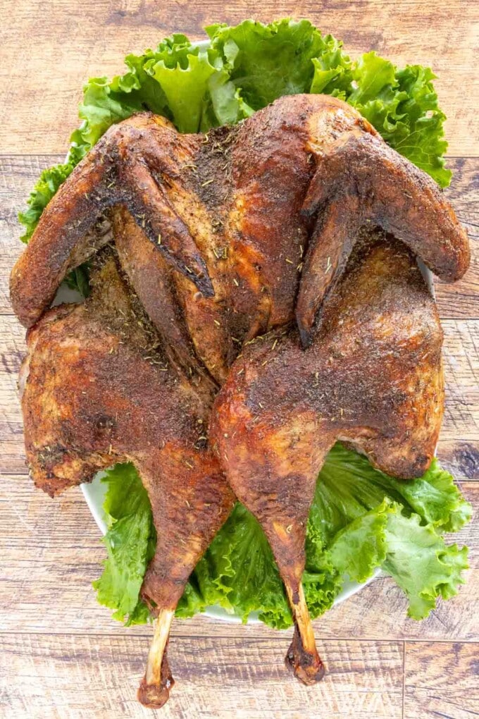 Roasted Spatchcock Turkey on a platter lined with romaine leaves.