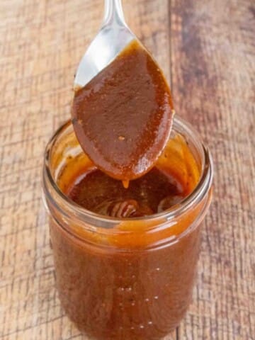 Memphis Barbecue Sauce in a glass jar with a spoon coming out.