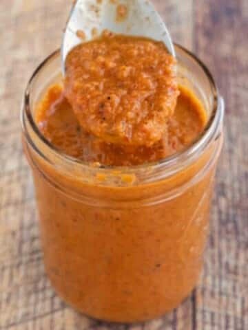 Peri-Peri Sauce in a glass jar with a spoon coming out of the jar.