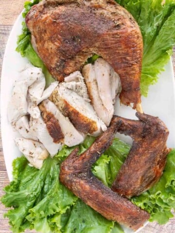 Cut up Spatchcock Turkey on a platter lined with romaine leaves.