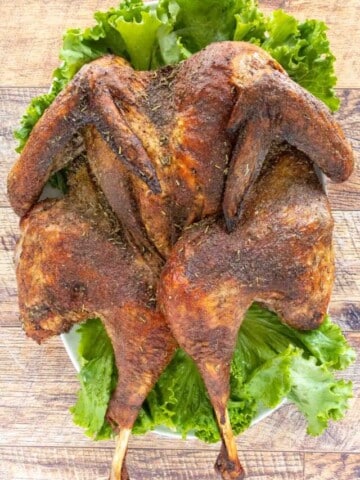 Roasted Spatchcock Turkey on a platter lined with romaine leaves.