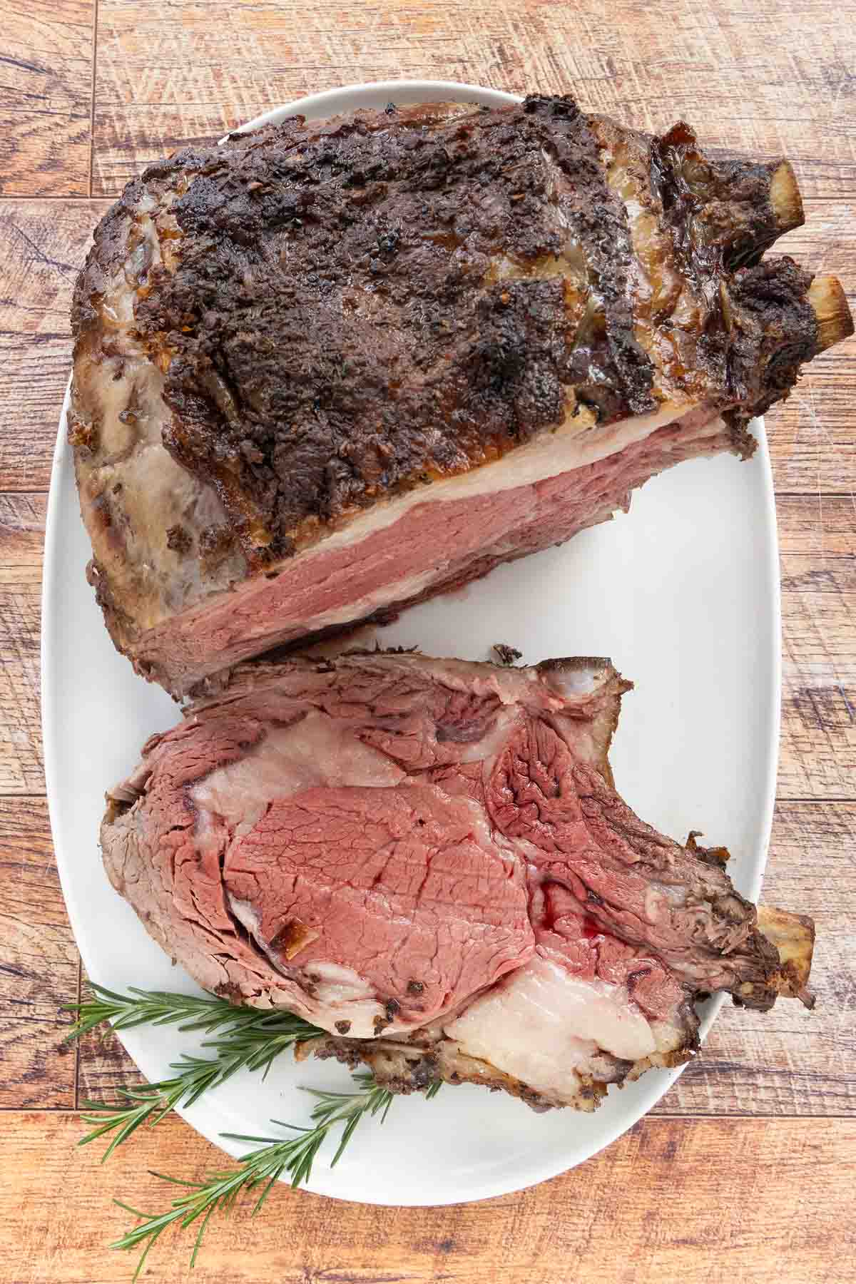 Slice of smoked prime rib on a white platter with the rest of the roast.