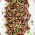 Beef Bulgogi on a bed of white rice on a white platter.