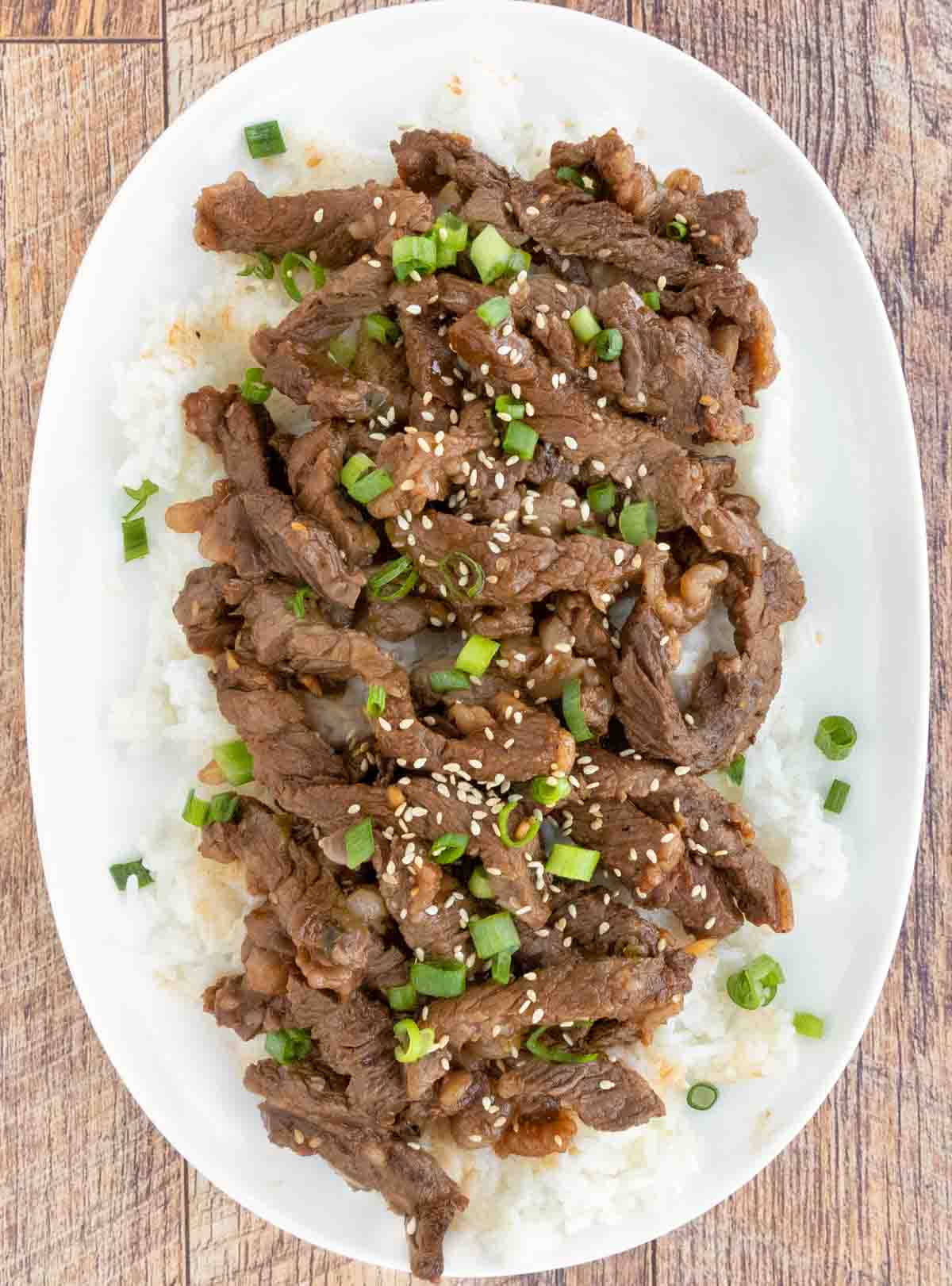 Beef Bulgogi on a bed of white rice on a white platter.