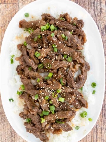 Beef Bulgogi on a bed of white rice on a white platter.