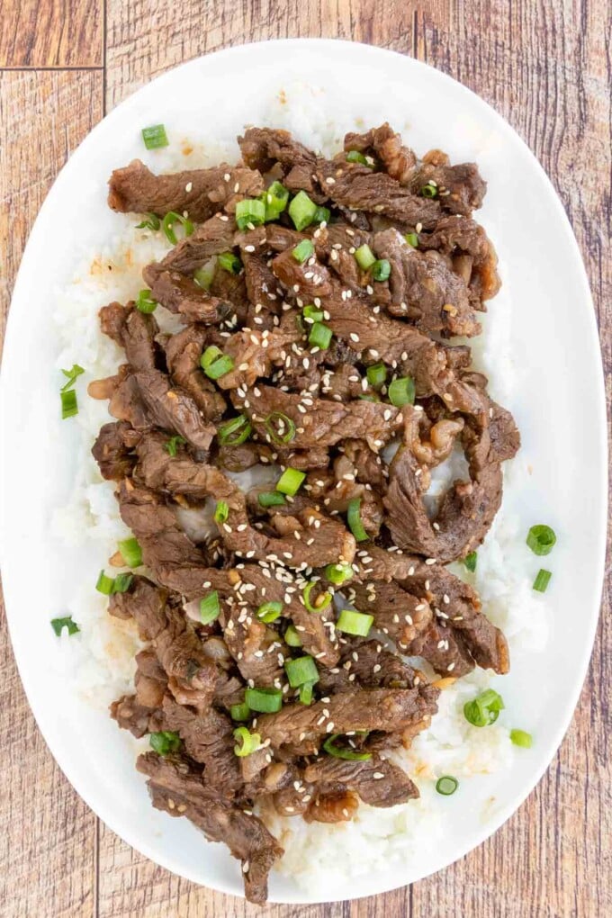 Beef Bulgogi on a bed of white rice on a white platter.