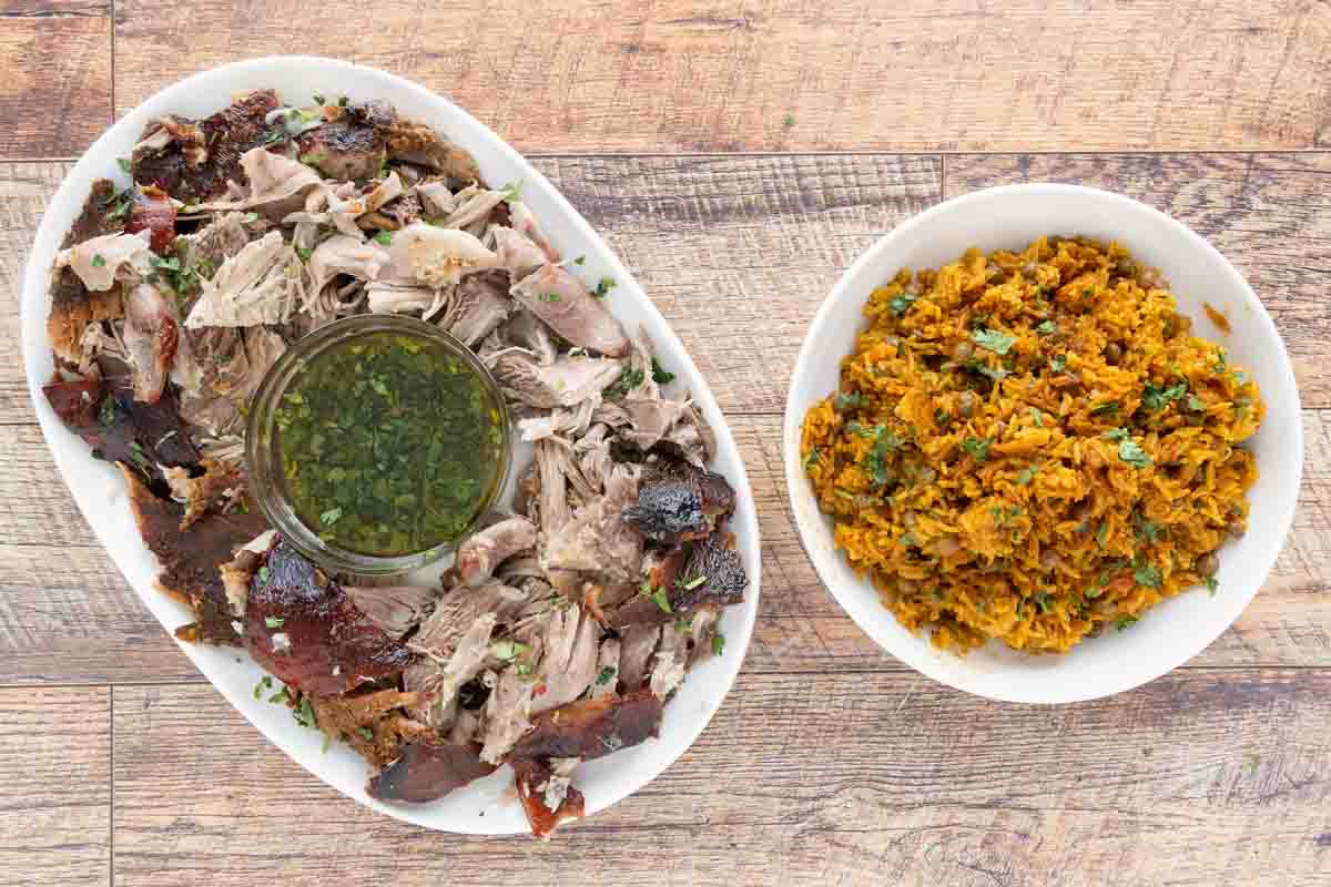 Arroz con Gandules (Puerto Rican rice) in a white bowl and Pernil on a white platter.