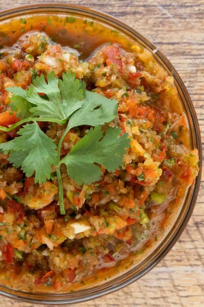 Sofrito in a large glass bowl with sprig of cilantro on top.