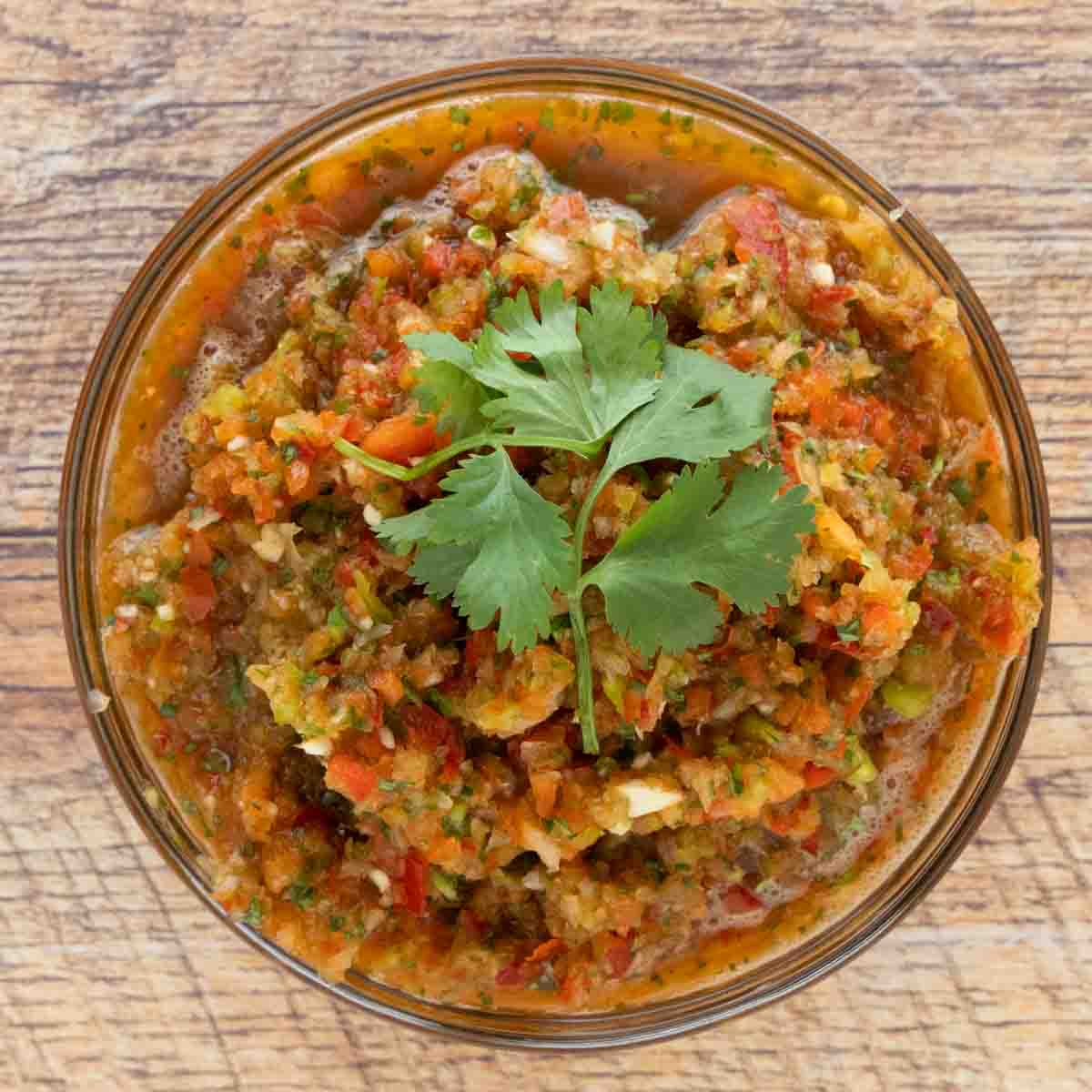 Sofrito in a large glass bowl with sprig of cilantro on top.