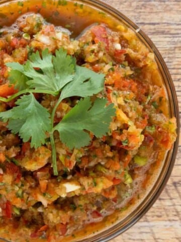 Sofrito in a large glass bowl with sprig of cilantro on top.