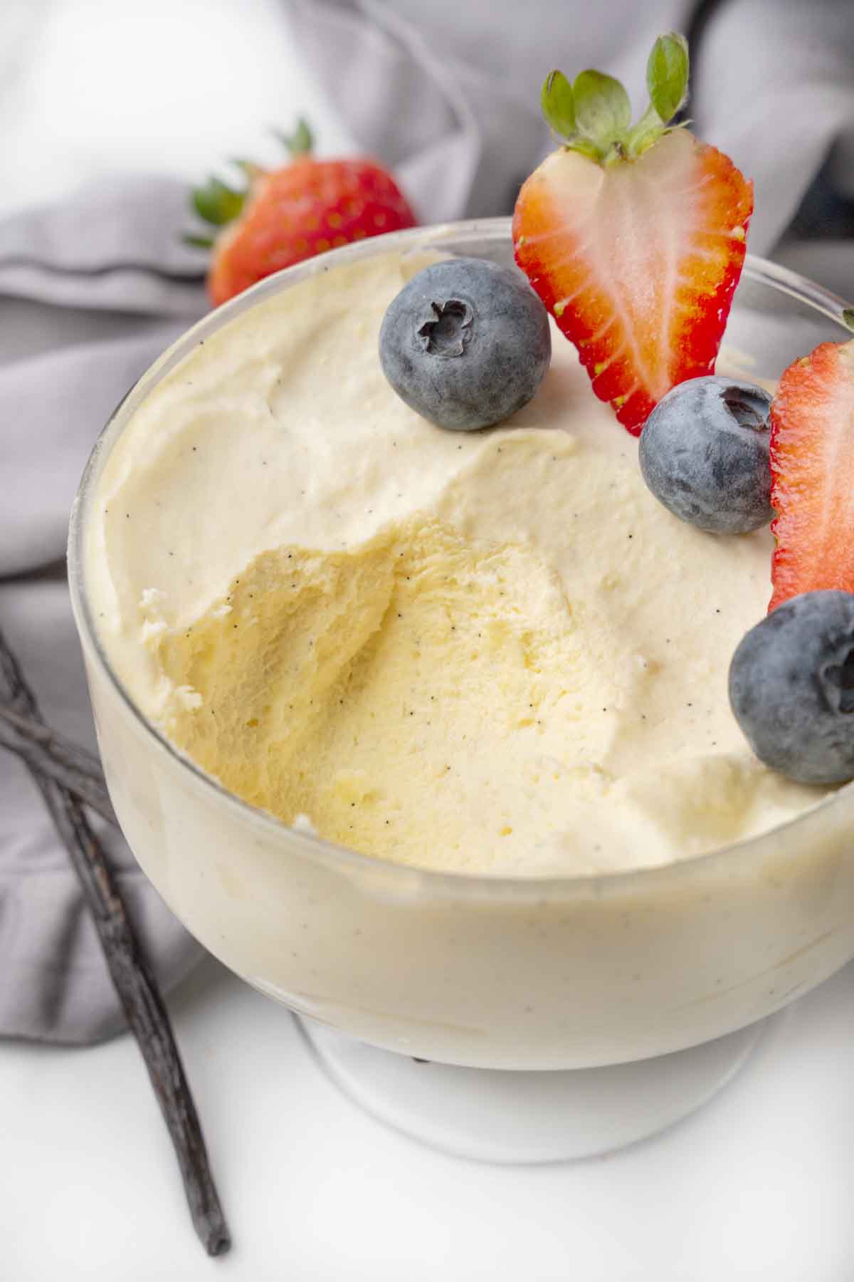 Bavarian cream in a dessert glass  garnished with berries, with a spoonful taken out.