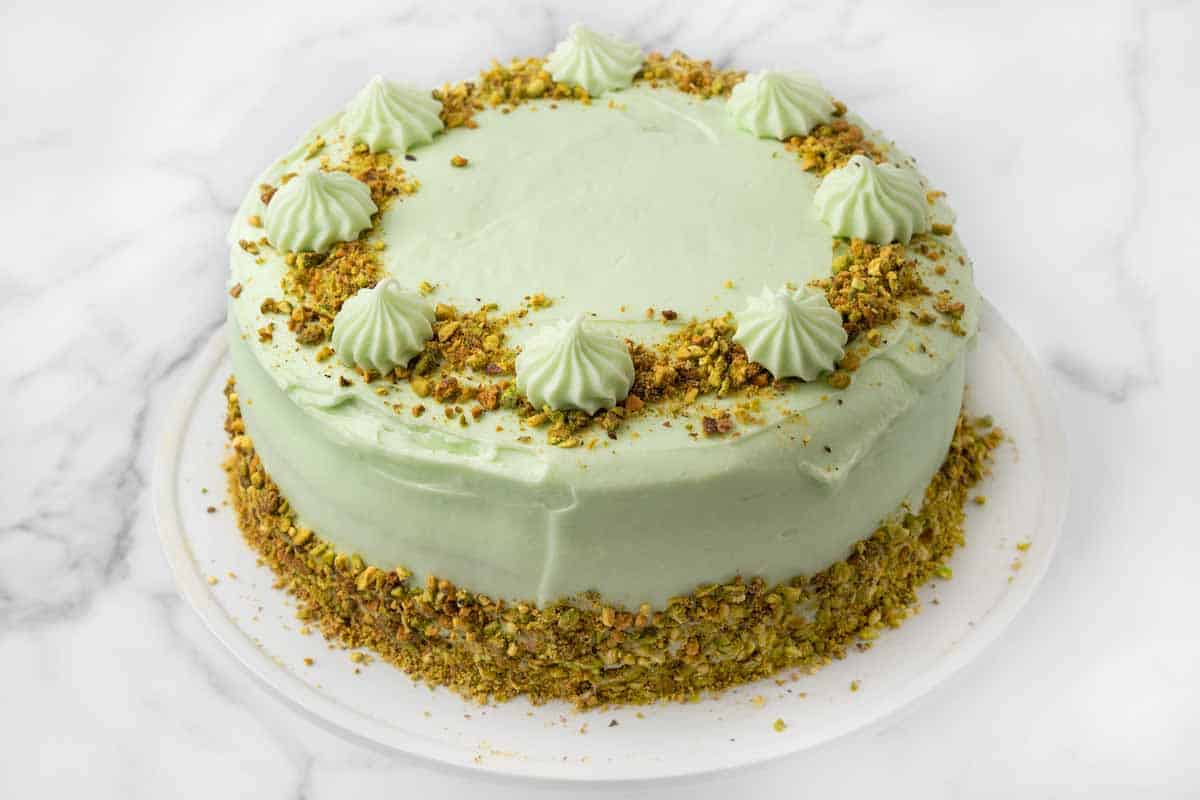 Whole Pistachio cake on a white platter.