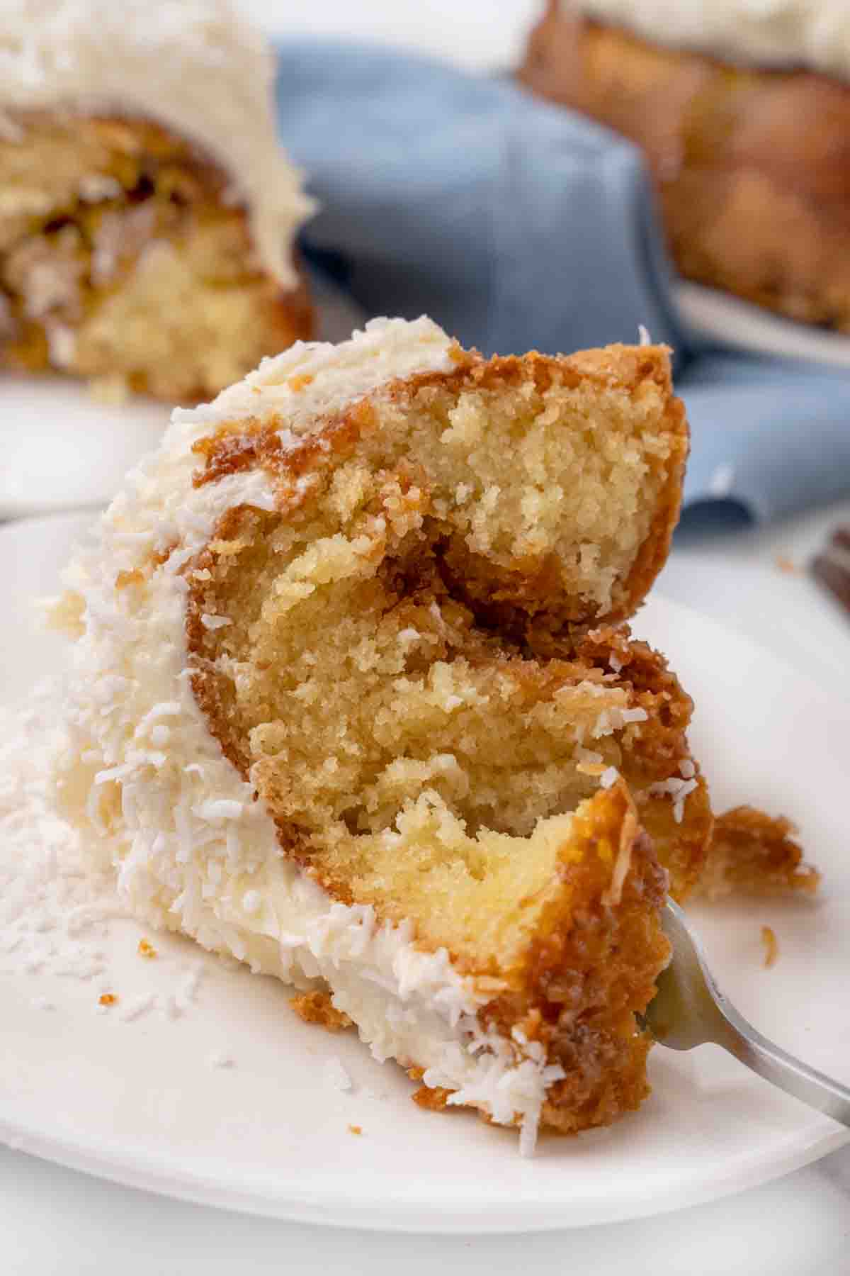 Slice of Tom Cruise Coconut Cake with a fork in it on a white plate.