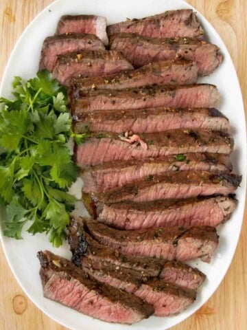 Sliced London broil on a white platter.