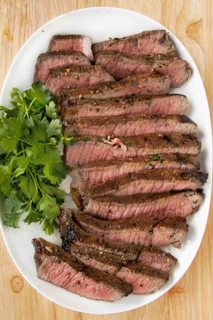 Sliced London broil on a white platter.