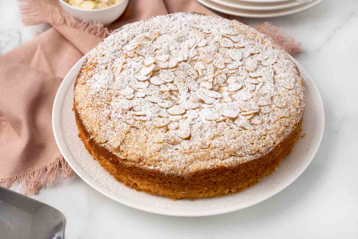 Whole almond cake on a white platter.