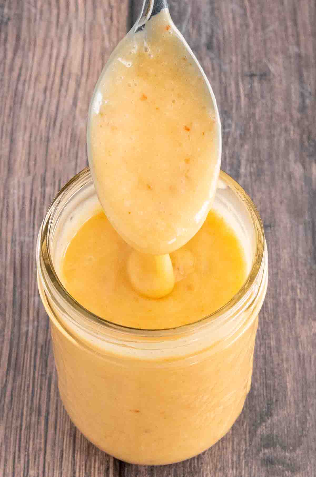 Bang Bang Sauce in a glass jar with a spoon coming out of the jar.