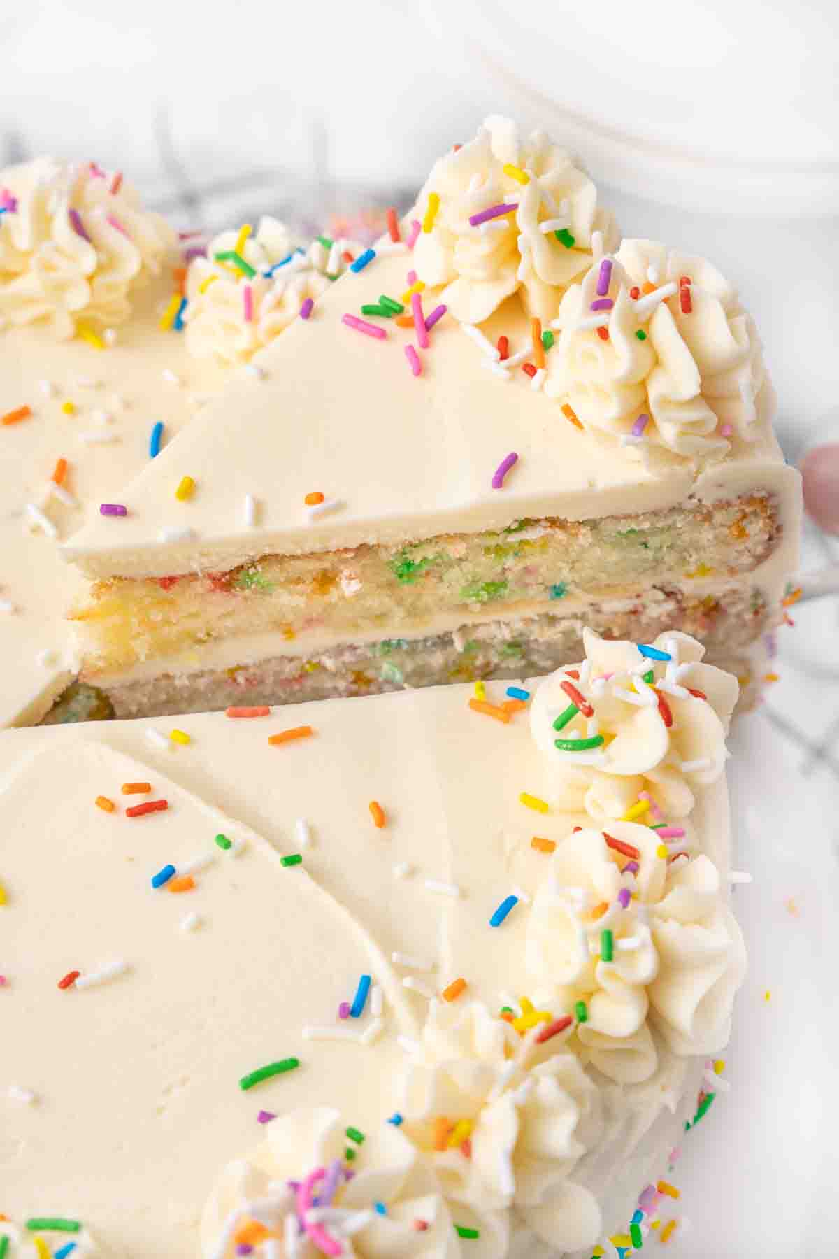 Slice of funfetti cake being taken out of the whole cake.