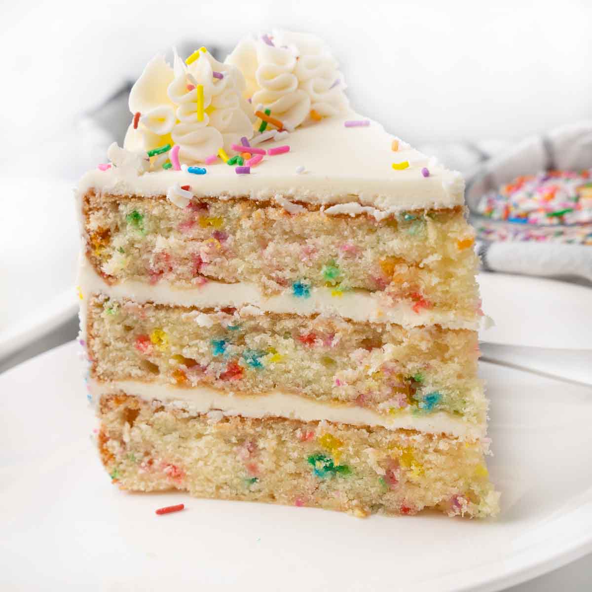 Slice of funfetti cake on a white plate.