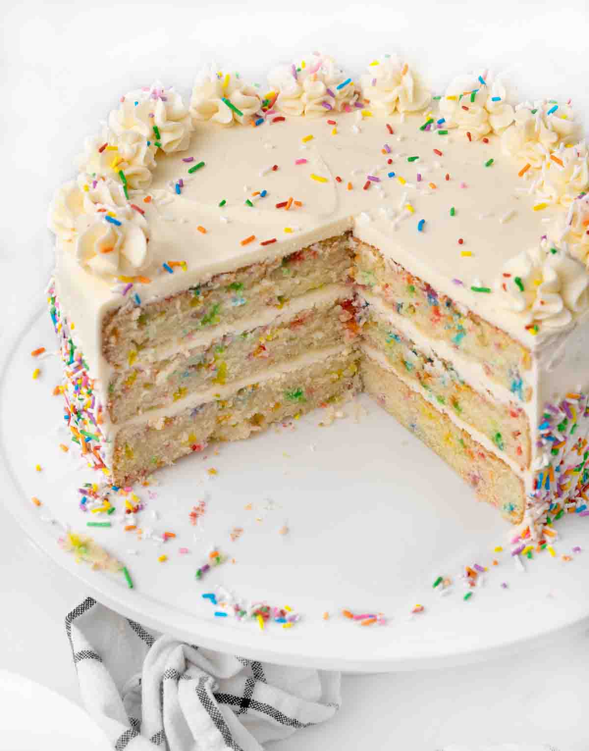 Whole funfetti cake with one quarter cut out.