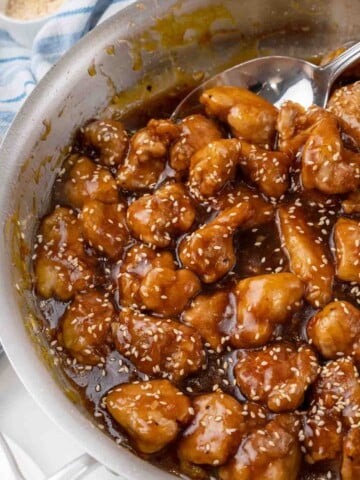 General Tso's chicken in the skillet with a spoon bringing some out.