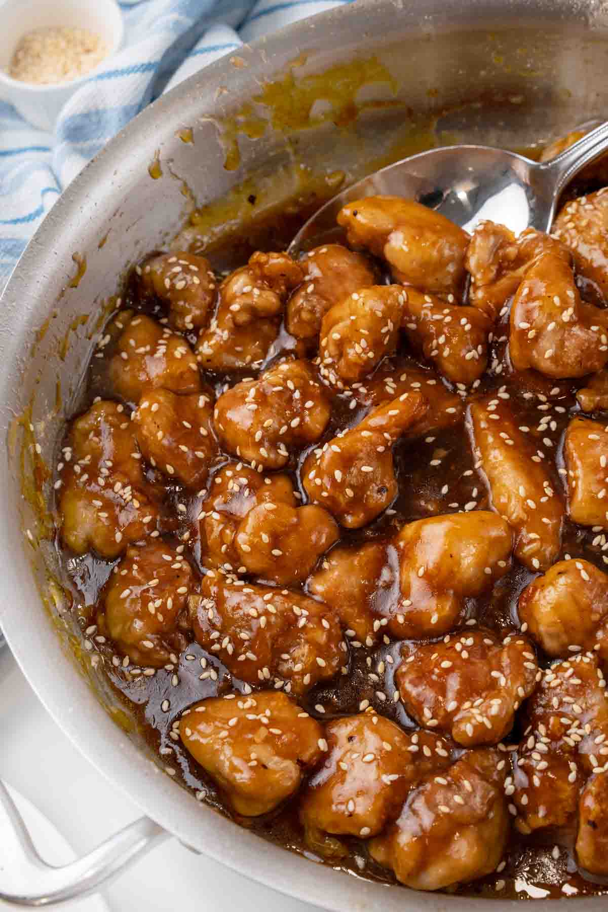 General Tso's chicken in the skillet with a spoon bringing some out.