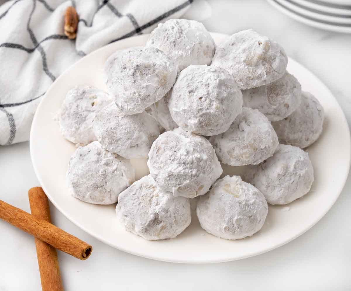 Mexican wedding cookies stacked on a white platter.