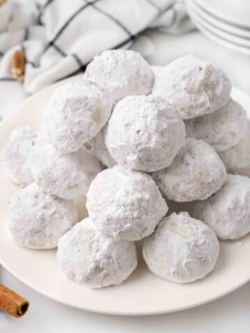 Mexican wedding cookies stacked on a white platter.