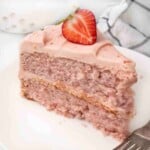 Slice of strawberry cake on a white plate with a fork.