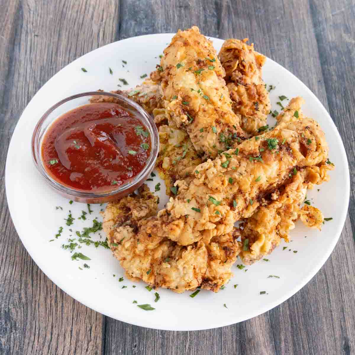 Fried chicken tenders with mumbo sauce on a white plate.