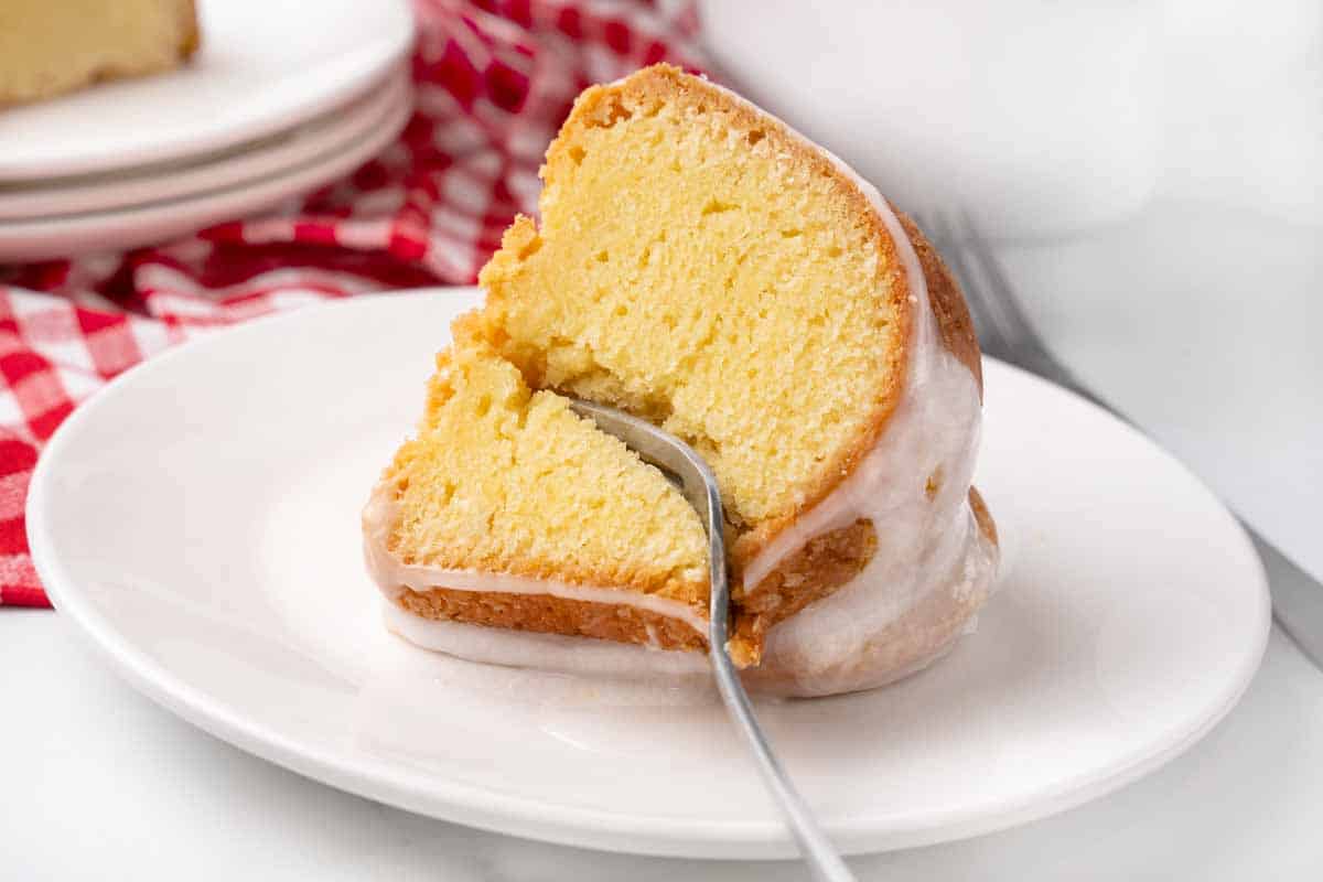 Slice of 7-up cake with a fork in it on a white plate.