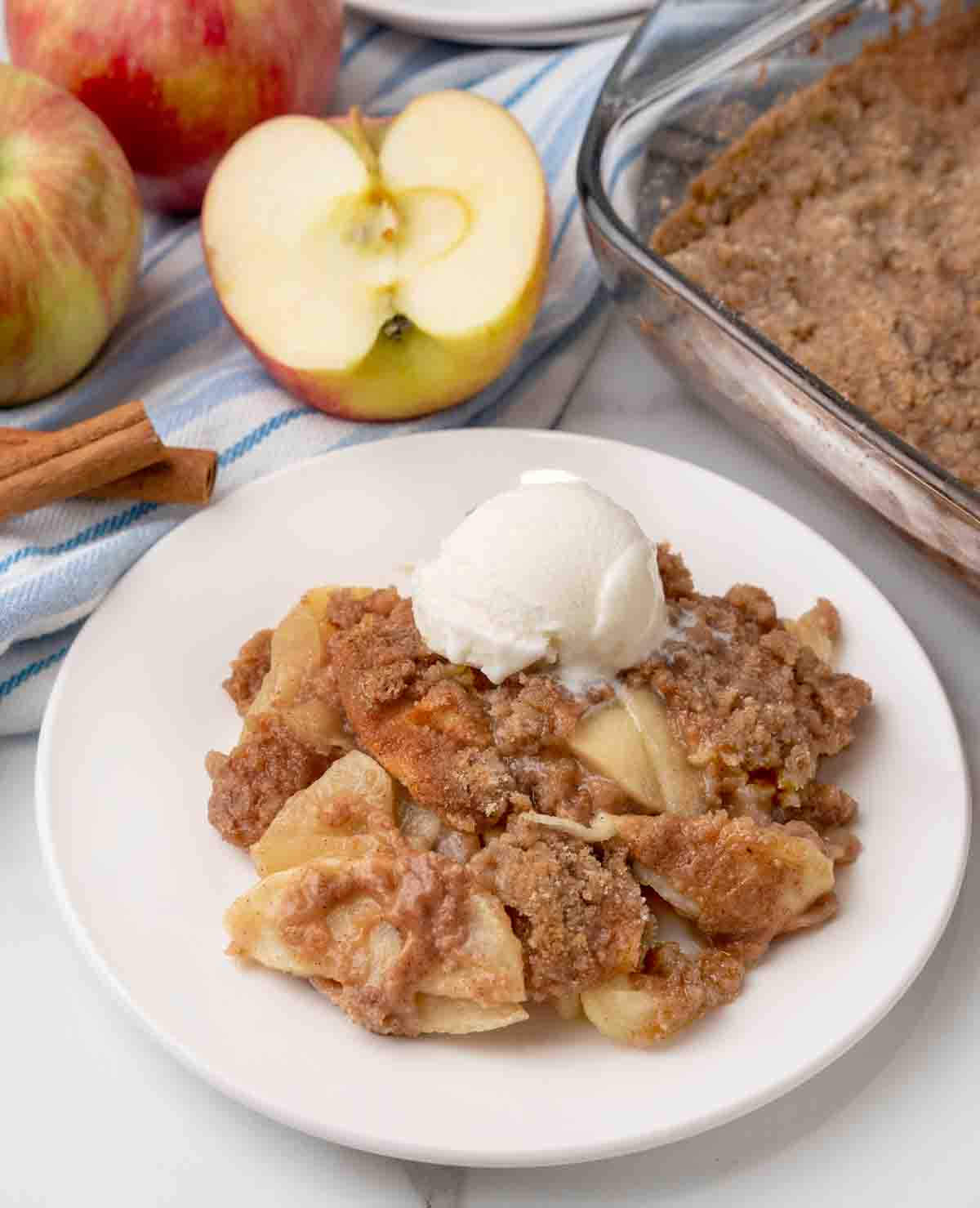 Apple Brown Betty with ice cream on a white plate.