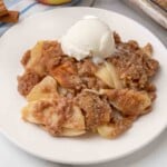 Apple Brown Betty with ice cream on a white plate.