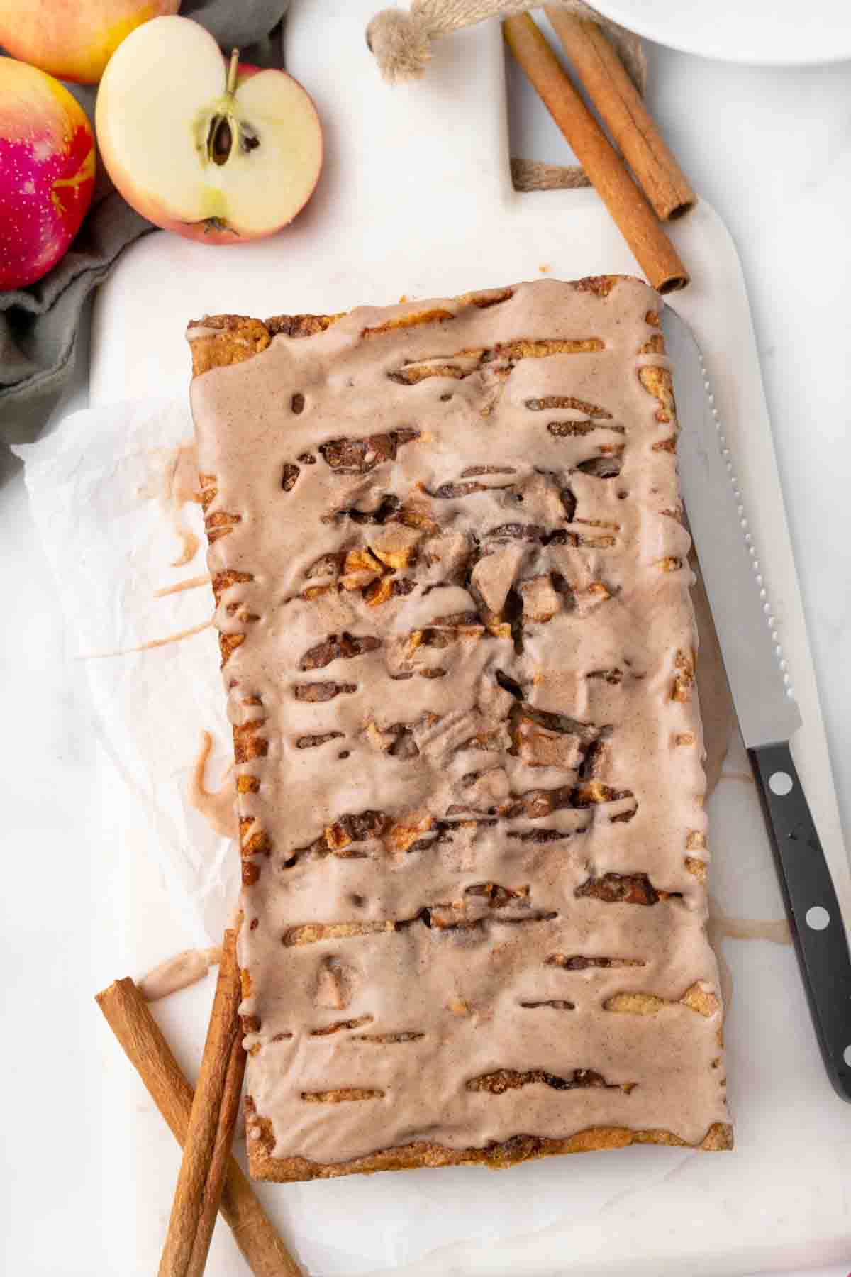 Whole loaf of apple fritter bread oh a white cutting board.