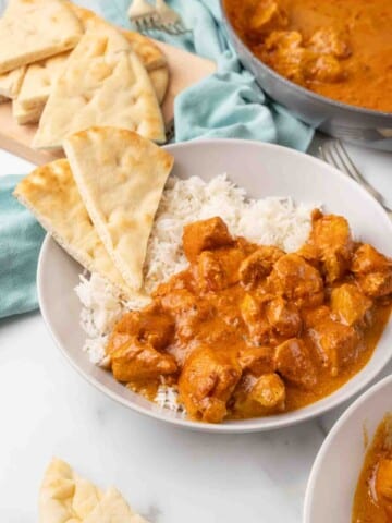 Butter chicken in a bowl with rice and naan bread.