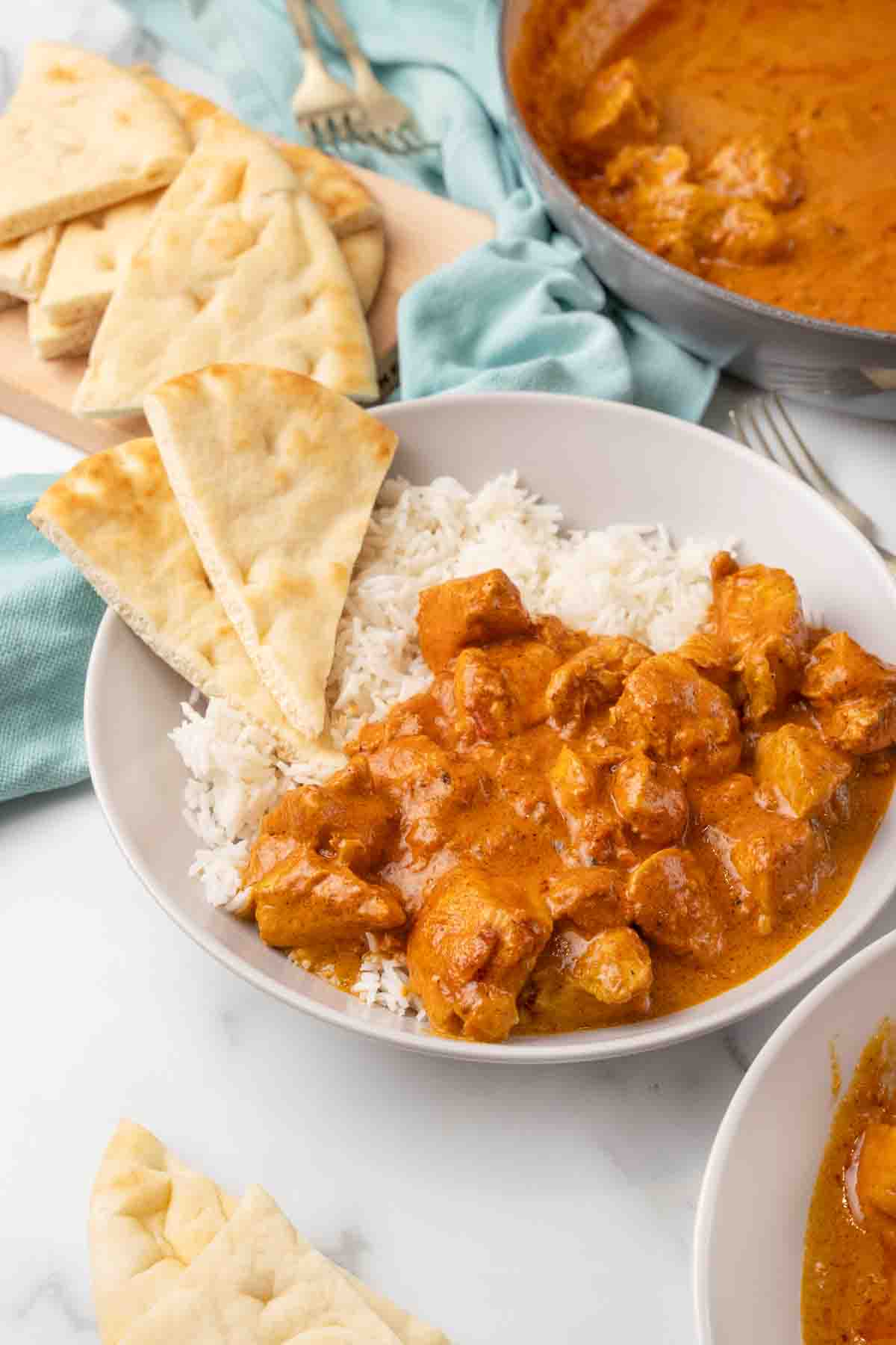 Butter chicken in a bowl with rice and naan bread.