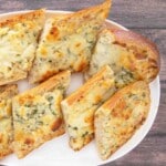 Sliced cheesy garlic bread on a white platter.