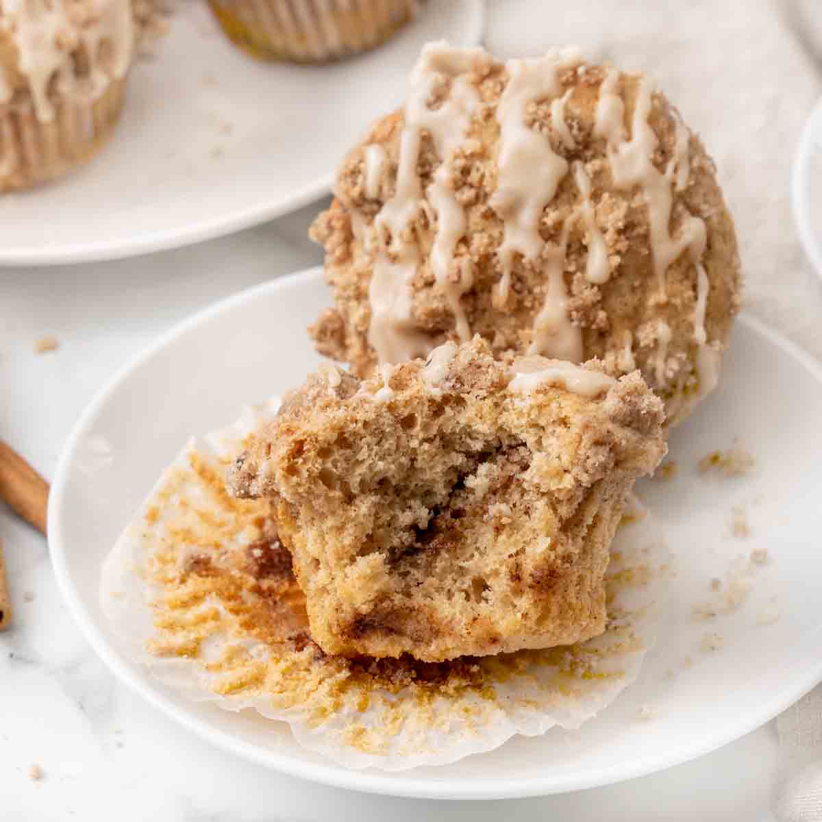 Coffee cake muffins with one showing the inside on a white plate.