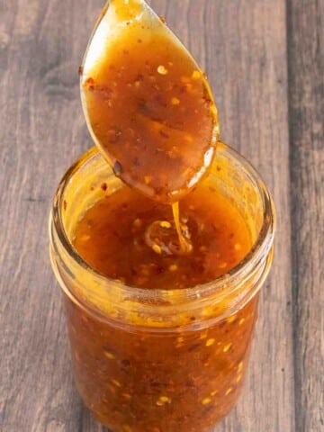 Hot honey in a glass jar with a spoon coming out of the jar.