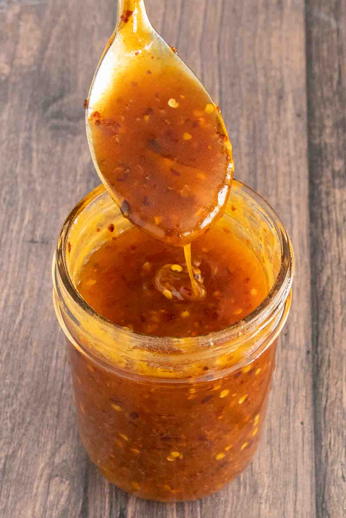 Hot honey in a glass jar with a spoon coming out of the jar.