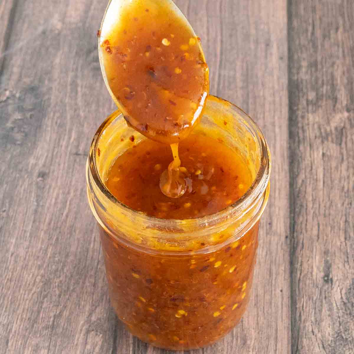 Hot honey in a glass jar with a spoon coming out of the jar.