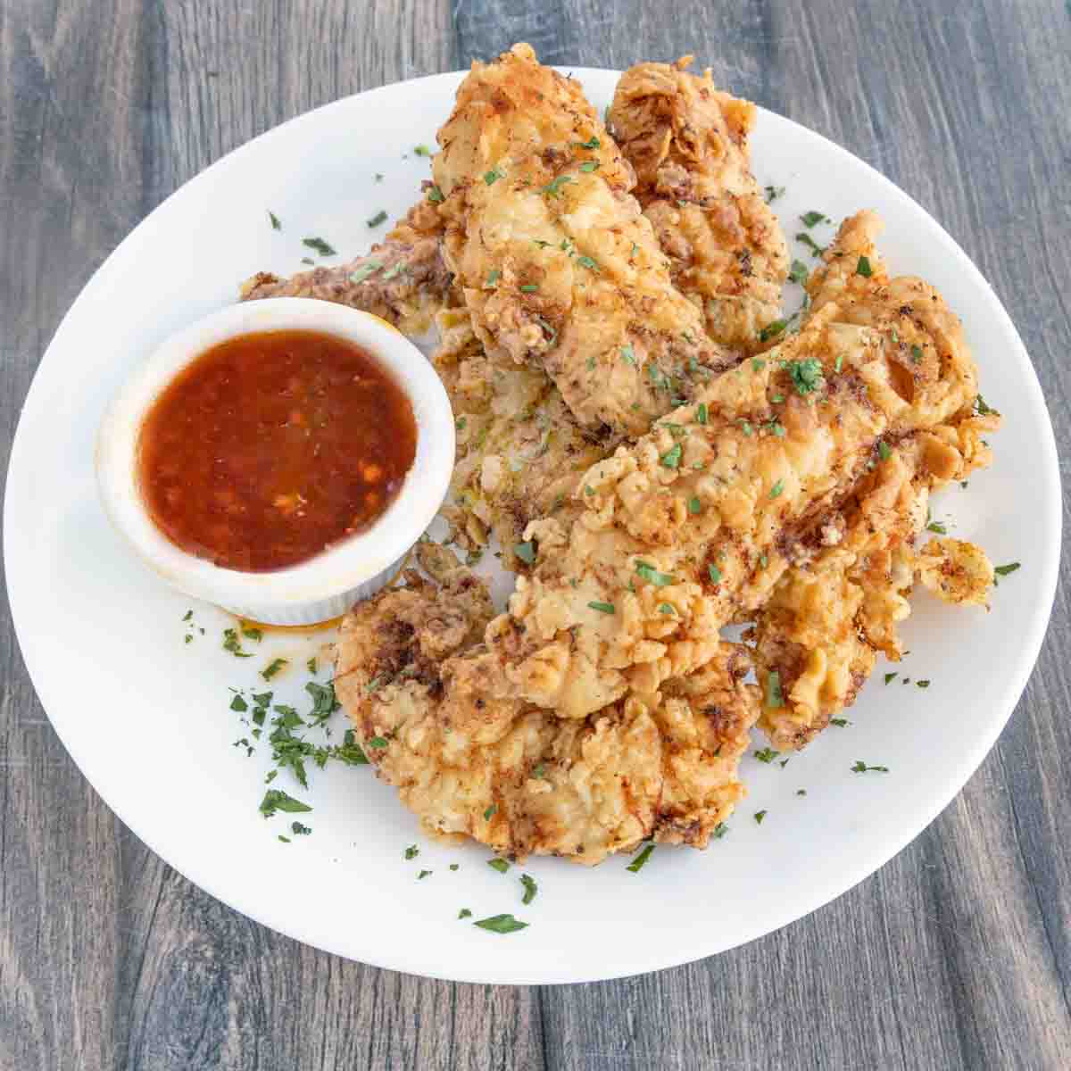 Hot honey with fried chicken tenders on a white plate.