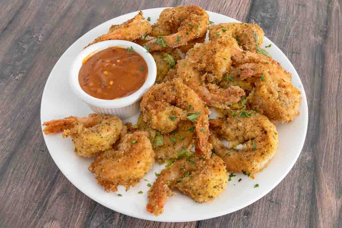 Hot honey with fried shrimp on a white plate.