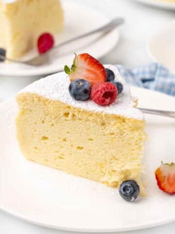 Slice of Japanese cheesecake with berries on a white plate.