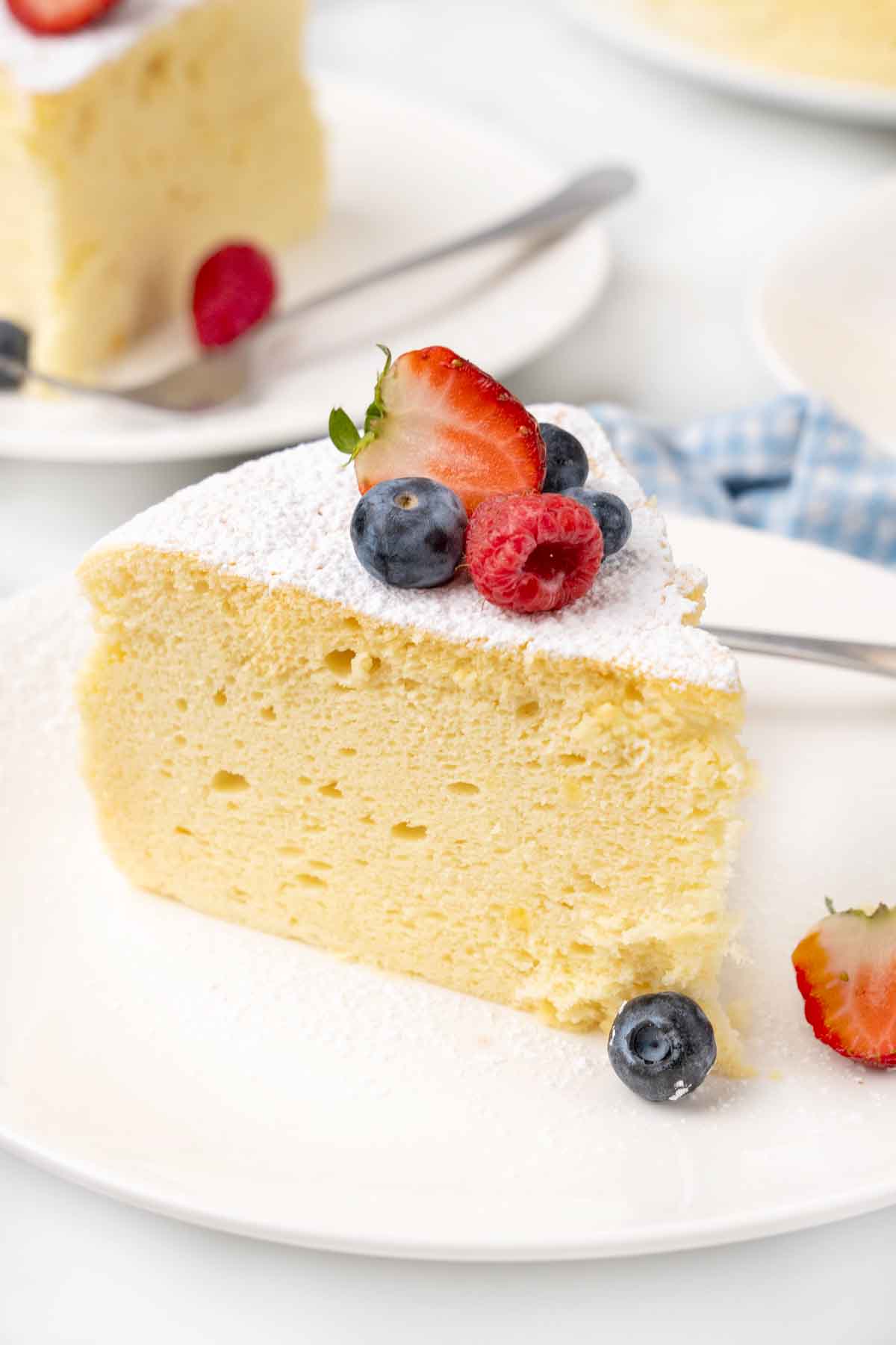 Slice of Japanese cheesecake with berries on a white plate.