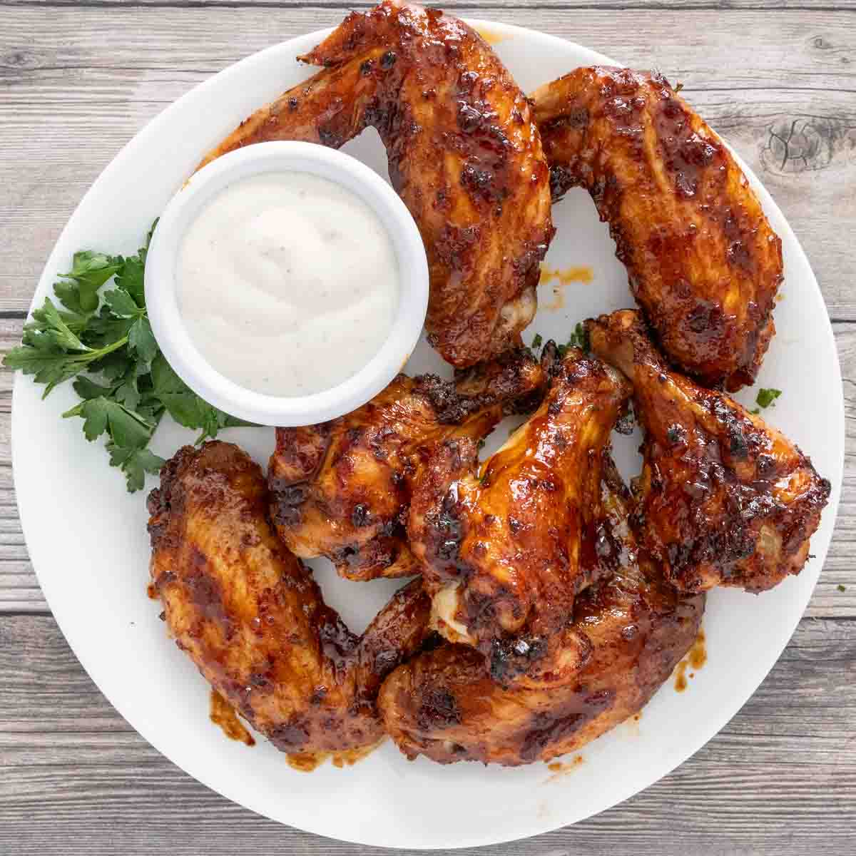 Korean chicken wings  on a white plate with dipping sauce.