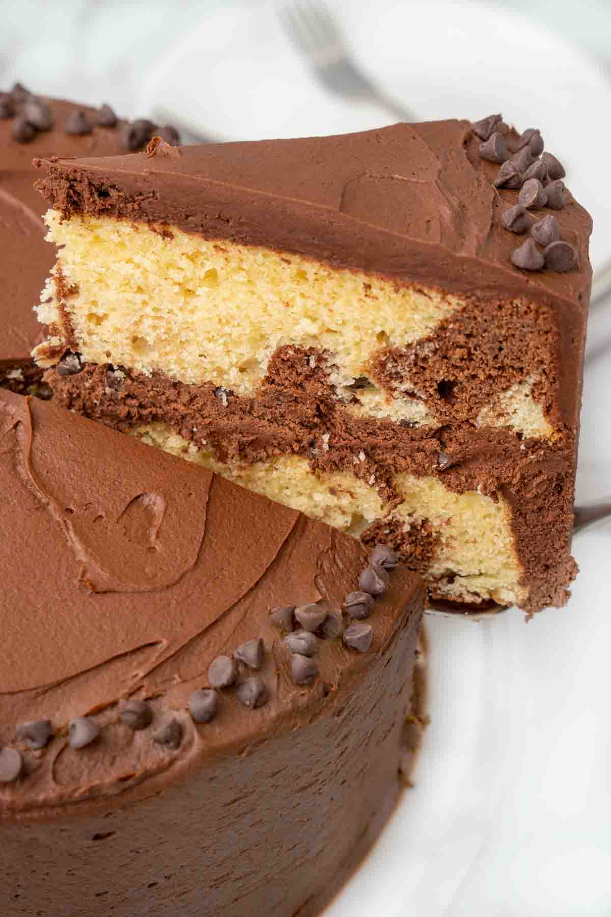 Slice of marble cake being taken out of the whole cake.