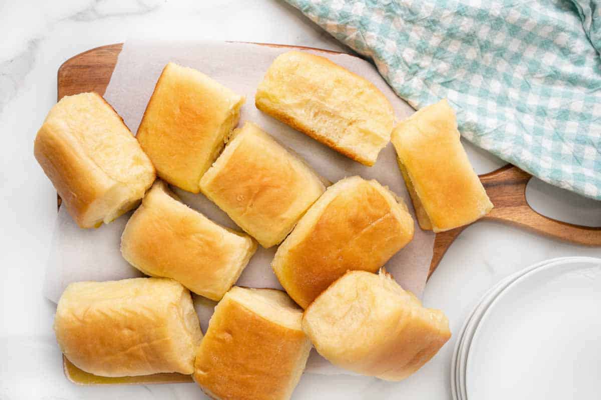 Parker house rolls on a cutting board with parchment paper.